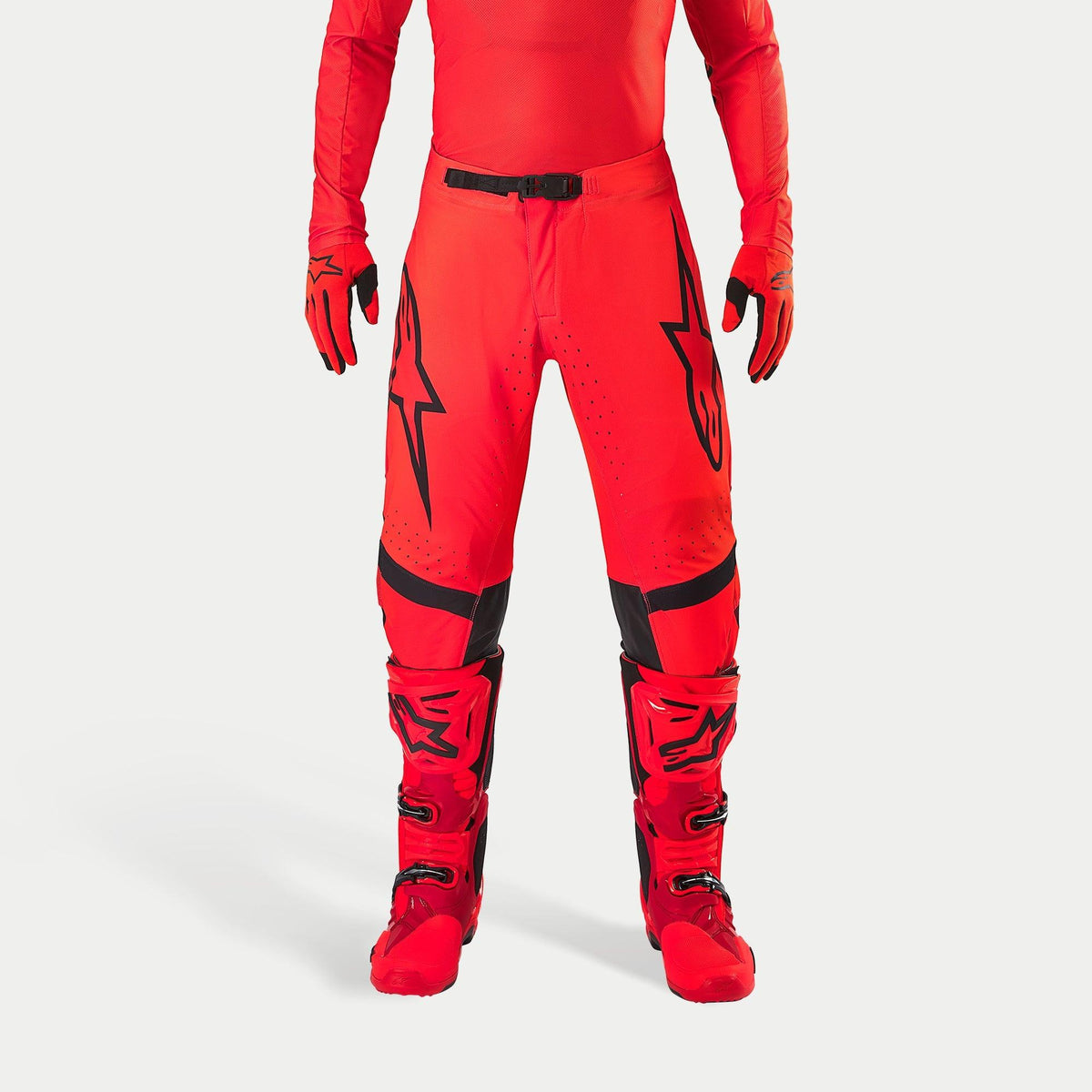 Alpinestars Supertech Ember LE Pants, pantalones de motocross, rojo flúor y rojo brillante con detalles en negro, con logotipos de estrellas negros en los muslos, hebilla de cintura y paneles en las rodillas negros, combinados con botas y guantes rojos a juego para un conjunto de competición coordinado.