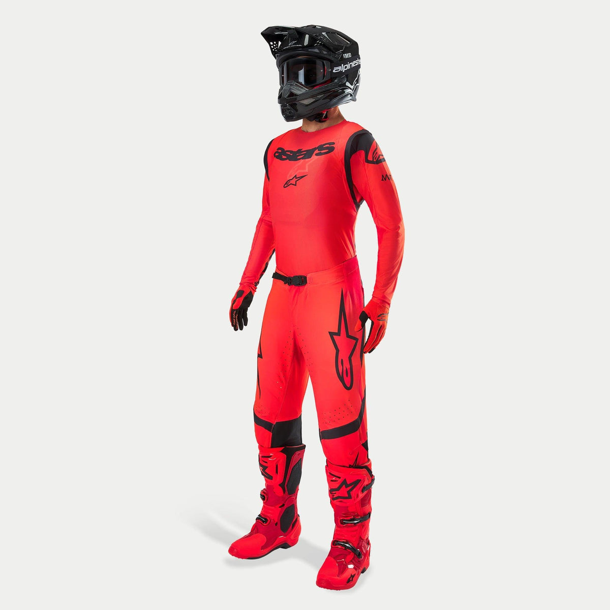 Piloto de motocross con equipo completo de competición, jersey y pantalones Supertech Ember LE en rojo flúor y negro, casco negro con gafas, botas y guantes a juego en rojo y negro, conjunto profesional coordinado para carreras todoterreno