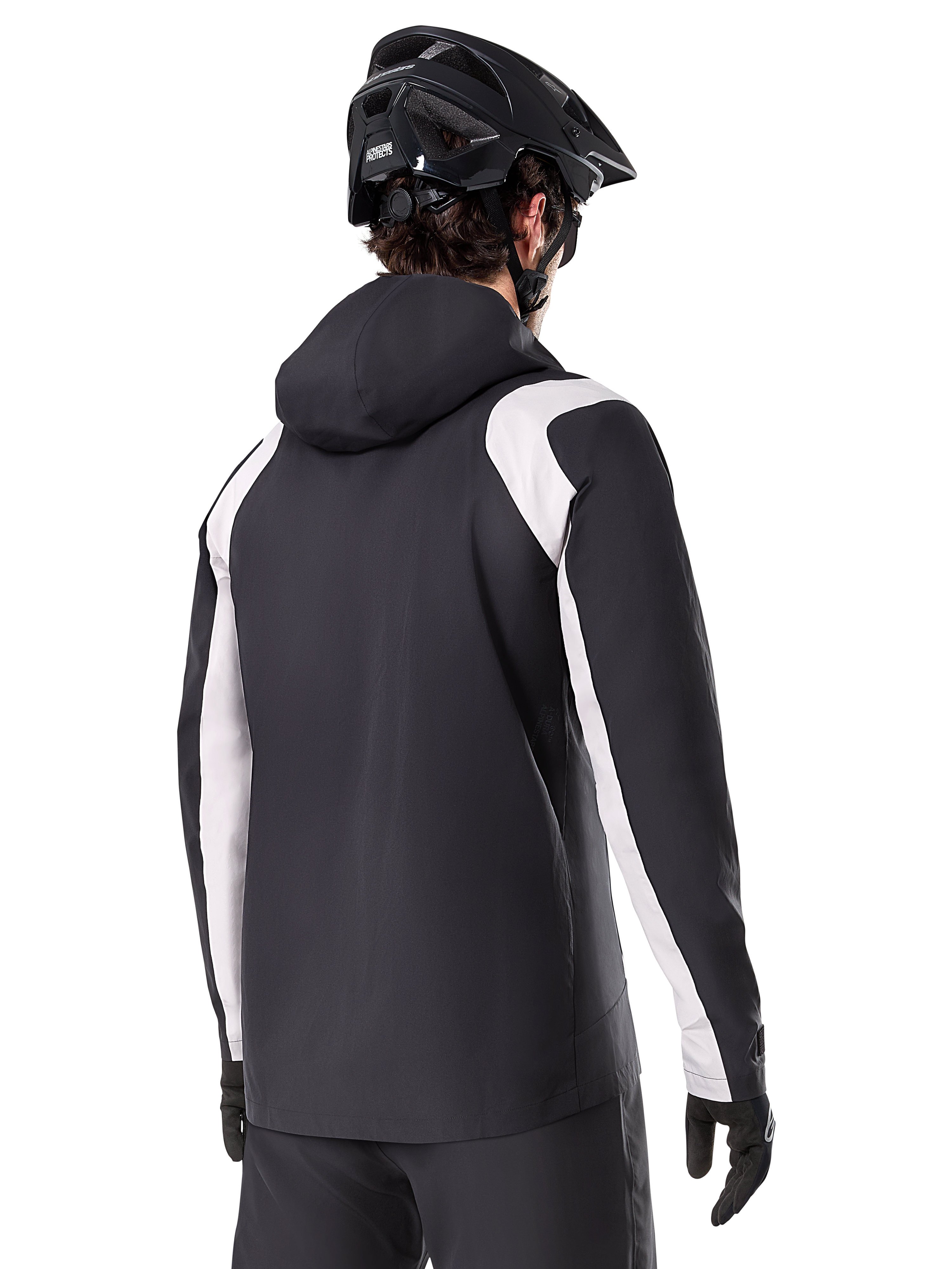 Alpinestars A-Dura Rain Jacket, chaqueta impermeable para ciclismo de montaña, negra con paneles blancos en las mangas, vista trasera de un ciclista con casco de MTB y guantes negros, construcción técnica impermeable de 2.5 capas, ropa de ciclismo de montaña