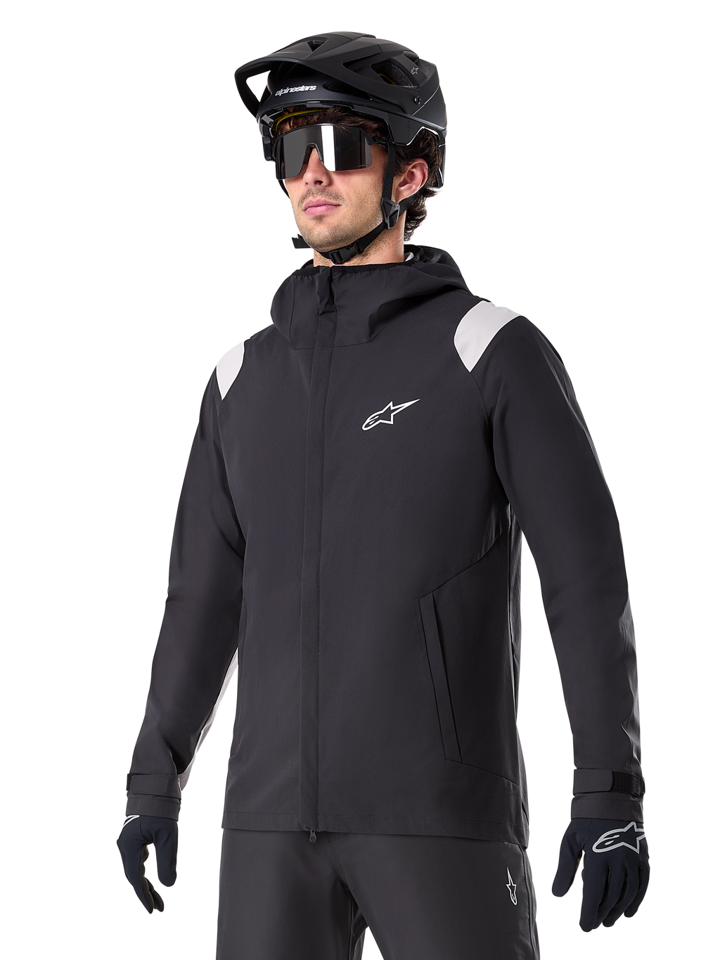 Alpinestars A-Dura Rain Jacket, chaqueta de lluvia para mountain bike, negra con detalles en los hombros en gris claro, usada por un ciclista con casco de MTB negro y gafas de sol, logo blanco en el pecho, construcción impermeable, coordinada con pantalones y guantes negros para ciclismo de montaña