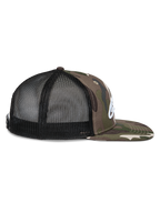 Gorra Alpinestars Corp Trucker, vista lateral, camuflaje verde y negro, visera plana con estampado de camuflaje, paneles traseros de malla negra, logo blanco bordado, gorra casual de estilo motorsport