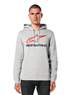 Alpinestars Always V3 Hoodie, gris claro jaspeado con logotipo de estrella en rojo y negro, lucida por un modelo, estilo urbano casual, capucha con cordones, bolsillo frontal tipo canguro, diseño con herencia del automovilismo