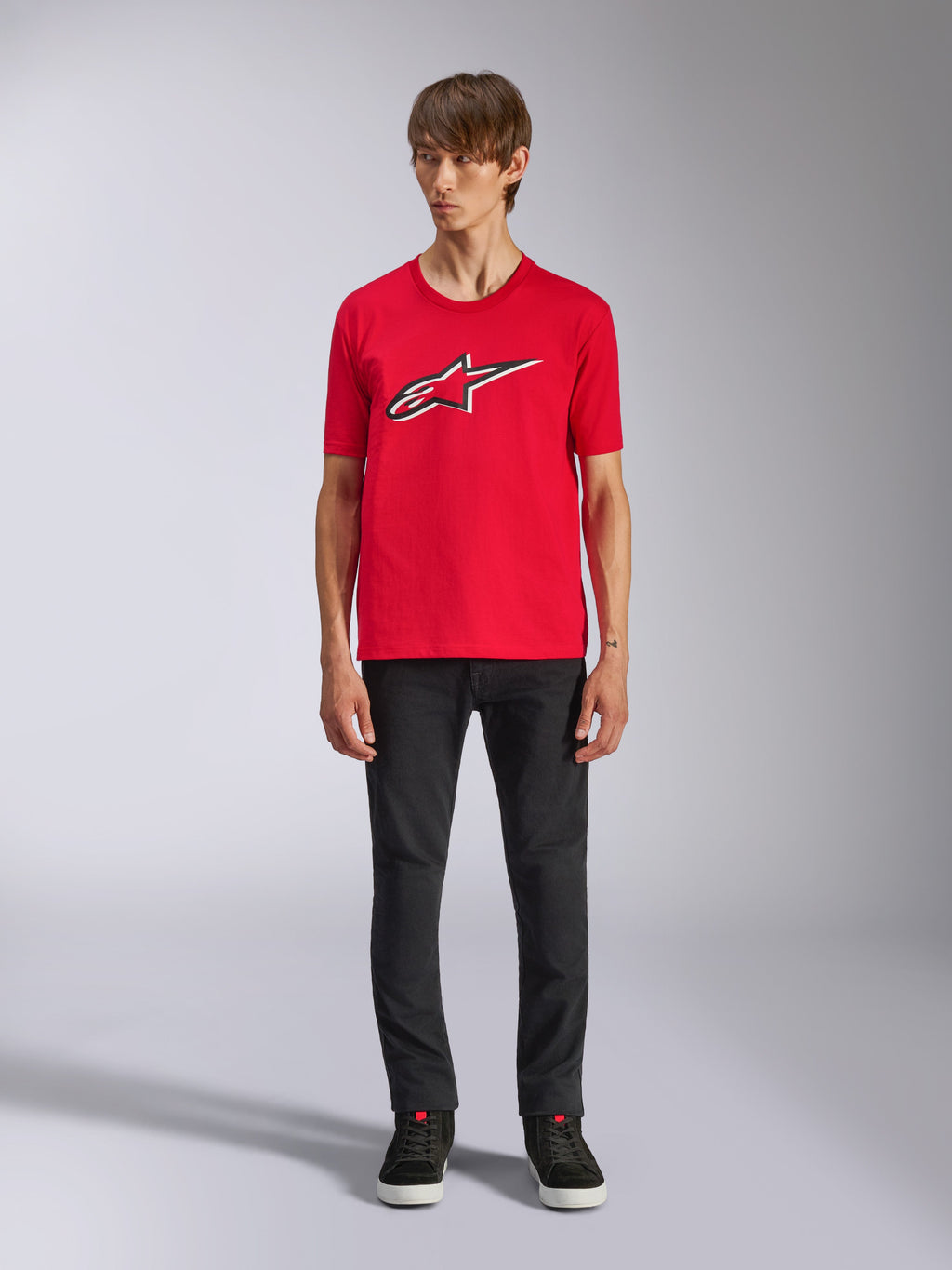 Camiseta Alpinestars Ageless Shadow CSF, camiseta de manga corta, roja, logo Ageless frontal con contornos blancos y negros, usada por un modelo con pantalones negros y zapatillas, ropa urbana casual de automovilismo