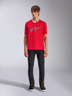 Camiseta Alpinestars Ageless Shadow CSF, camiseta de manga corta, roja, logo Ageless frontal con contornos blancos y negros, usada por un modelo con pantalones negros y zapatillas, ropa urbana casual de automovilismo