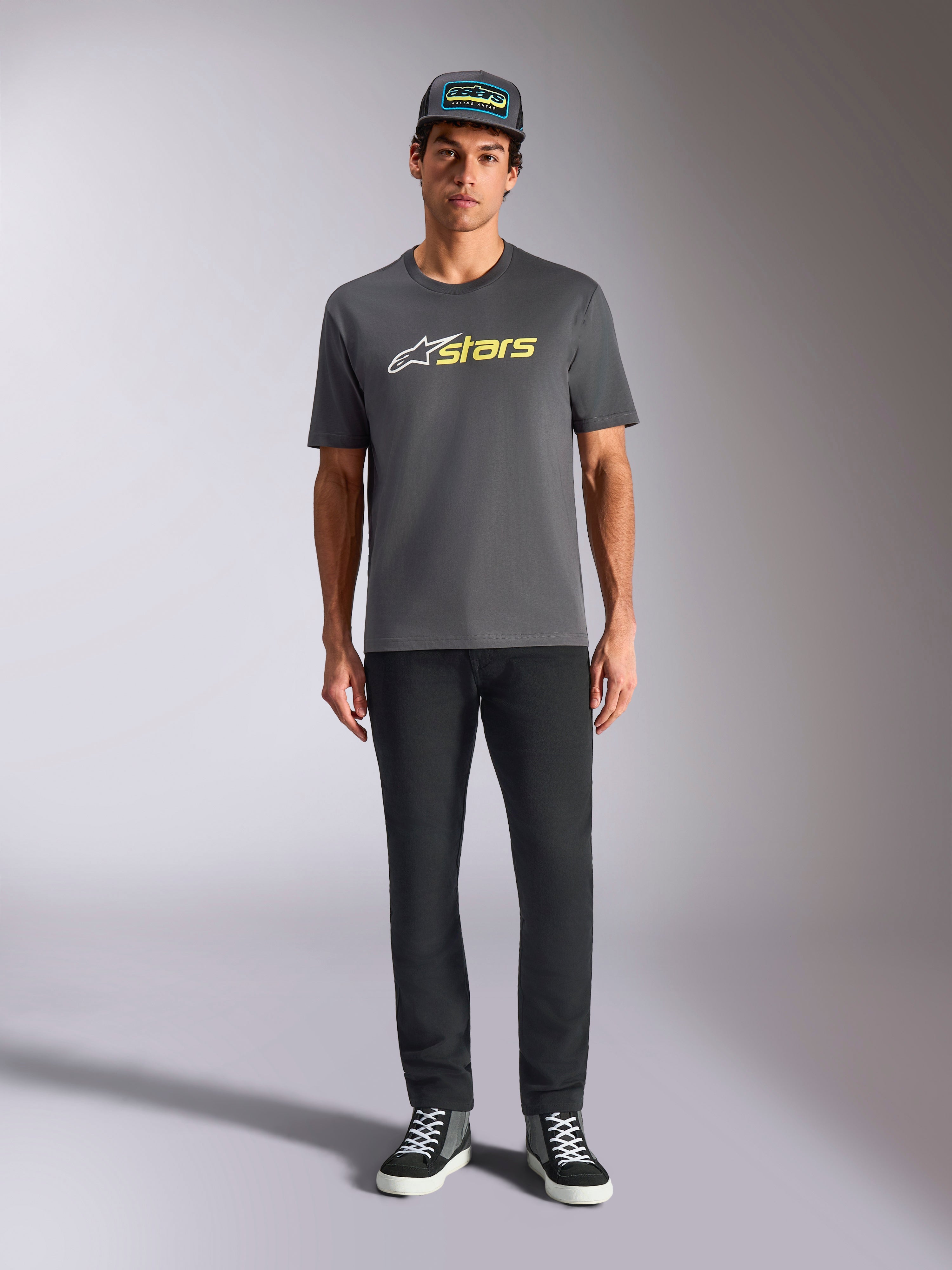 Alpinestars Blaze 2.0 CSF Tee, Short Sleeve T-Shirt, Charcoal Gray with White and Hi-Vis Yellow logo, worn with black pants and a matching trucker hat, casual motorsport lifestyle