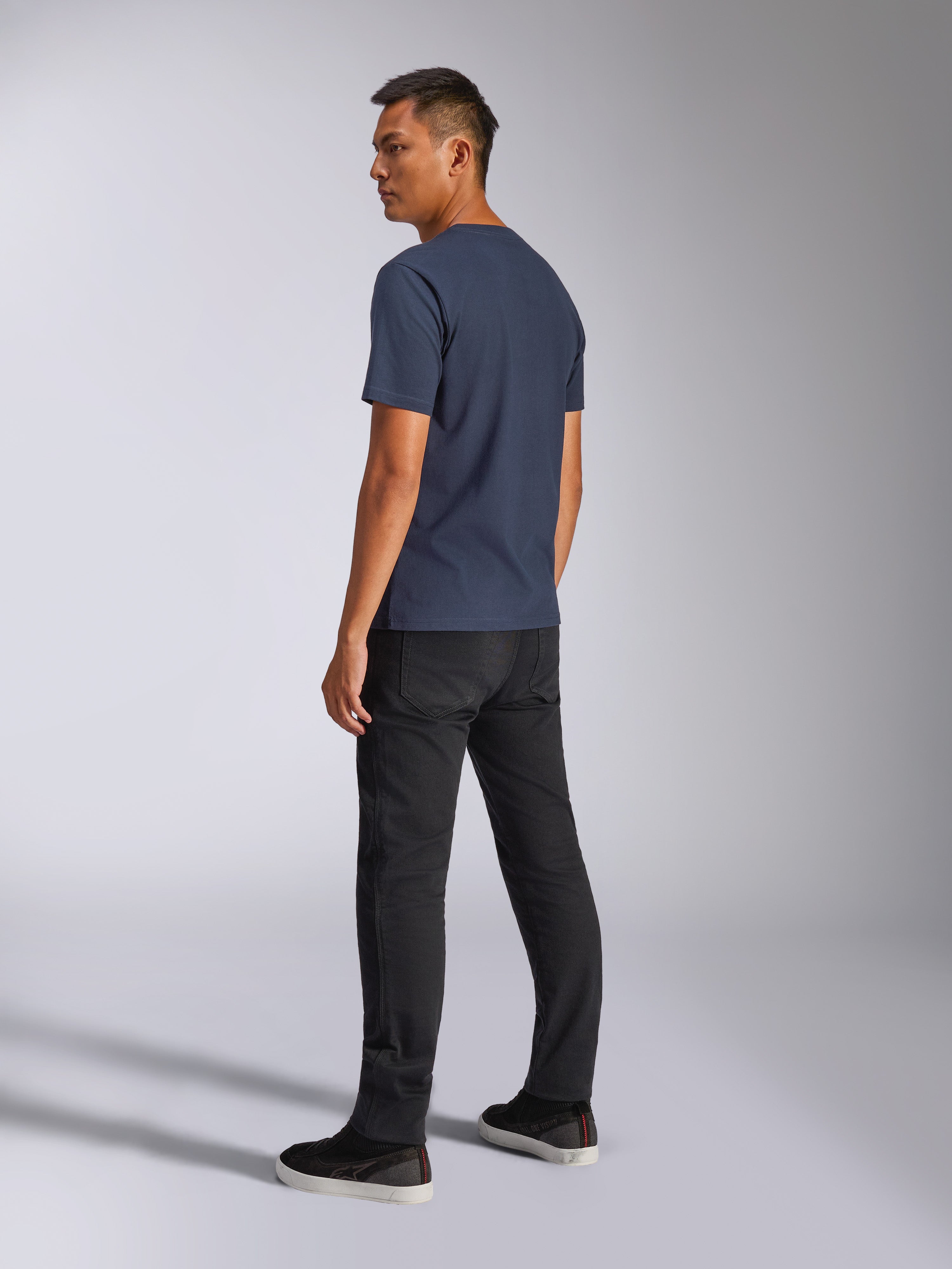 Alpinestars Blaze 2.0 CSF Tee, camiseta de manga corta, azul marino, vista posterior en modelo, combinada con pantalones negros y zapatillas, ropa urbana casual inspirada en el automovilismo