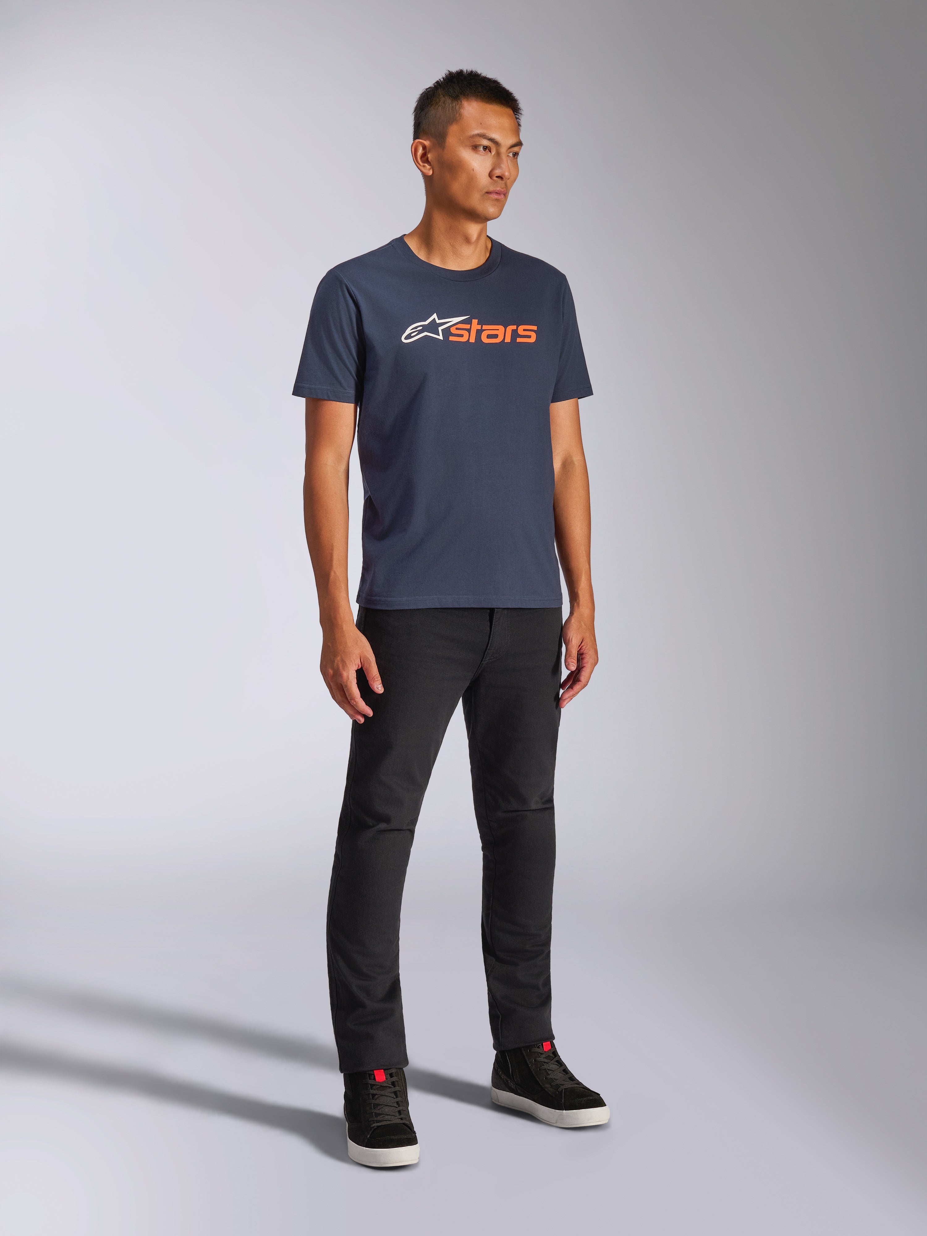 Alpinestars Blaze 2.0 CSF Tee, camiseta de manga corta, azul marino con el logotipo Blaze en blanco y naranja, vestida por un modelo con pantalones negros y zapatillas, estilo urbano casual inspirado en el automovilismo