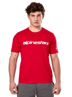 Alpinestars Linear Wordmark 2.0 CSF Tee, camiseta de manga corta roja, marca de palabra lineal blanca en el pecho y logotipo Ageless en la manga, lucida por un modelo masculino con pantalones de chándal grises, estilo urbano casual inspirado en el automovilismo
