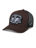 Gorra Alpinestars Heritage Patch Trucker Hat, color marrón y negro, con un gran parche frontal con bordado de rueda alada y texto 'RACING AHEAD EST. 1963', malla trasera negra transpirable, visera curva y logo de estrella blanco en el lateral, accesorio casual de estilo motorsport