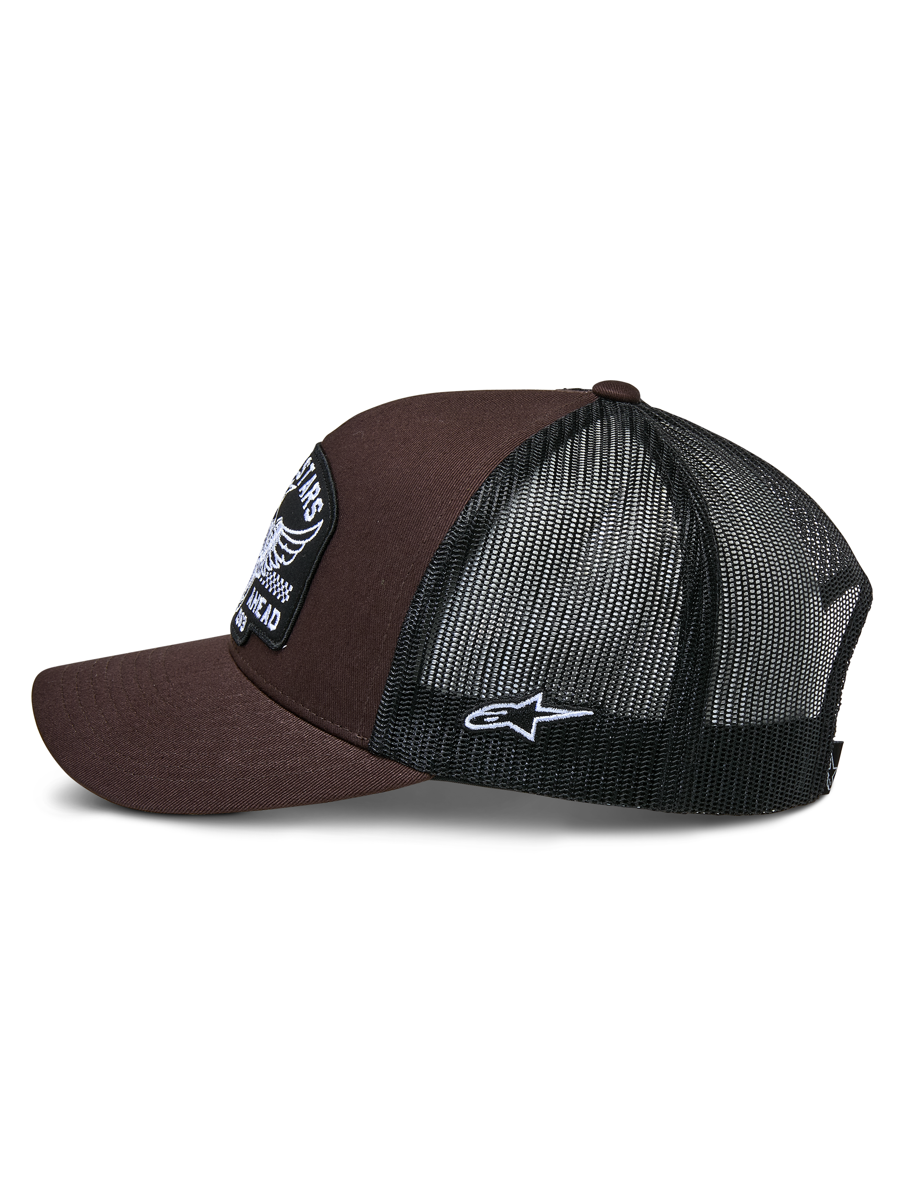 Gorra Trucker Heritage Patch de Alpinestars, marrón y negro, vista lateral que muestra la parte frontal de sarga marrón y la parte trasera de malla negra, parche lateral blanco con el logotipo Ageless, corona estructurada y visera curva