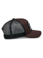 Alpinestars Heritage Patch Trucker Hat, marrón y negro, con una corona estructurada, un parche bordado grande, visera curva y parte trasera de malla negra, diseño casual inspirado en el automovilismo