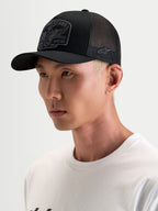 Gorra Alpinestars Heritage Patch, gorra trucker sportswear, negra y gris, con visera curva y parche delantero bordado, vista en modelo