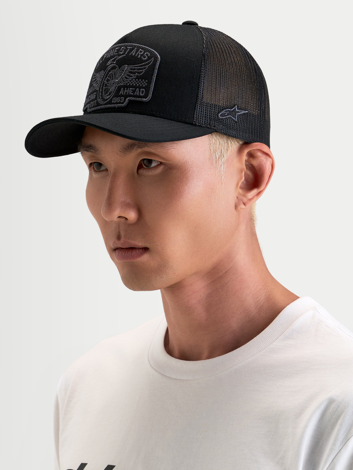 Gorra Alpinestars Heritage Patch, gorra trucker sportswear, negra y gris, con visera curva y parche delantero bordado, vista en modelo
