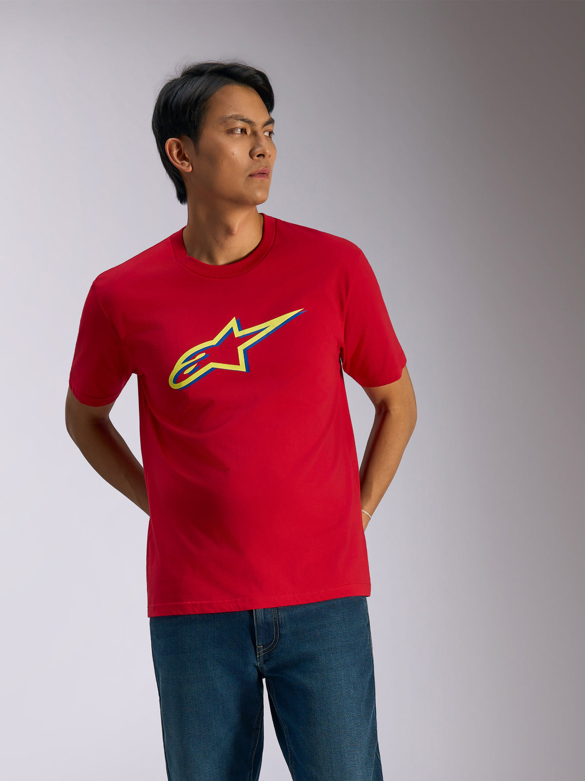 Camiseta Alpinestars Ageless Shadow CSF, camiseta de manga corta, roja, logotipo con efecto de sombra en rojo, amarillo y azul en el pecho, ropa urbana informal de automovilismo combinada con vaqueros azules