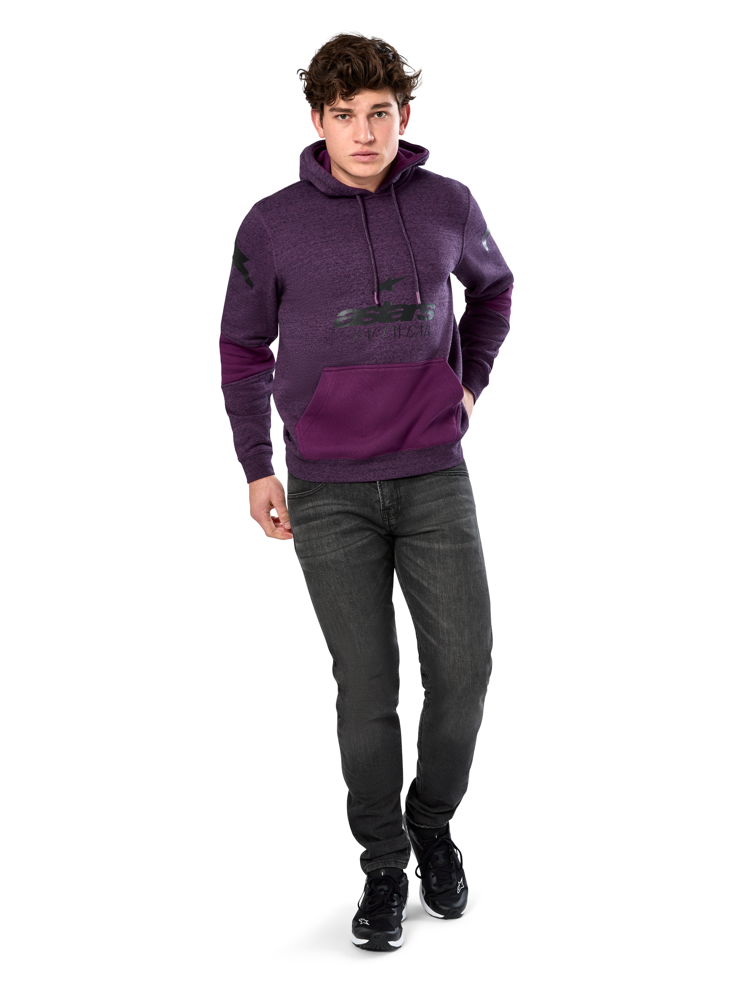 Sudadera Alpinestars Perpetuate Hoodie, ropa urbana casual, forro polar jaspeado púrpura con bloques de tela púrpura oscuro en el bolsillo canguro y mangas, logotipo negro en el pecho, capucha con cordón, lucida por modelo con vaqueros gris oscuro y zapatillas negras