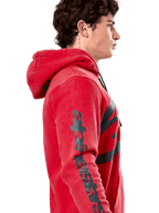 Alpinestars Unbound Hoodie, sudadera roja de forro polar, perfil lateral que muestra la marca denominativa Alpinestars en gris oscuro en la manga, acabado teñido en prenda con capucha con cordón, ropa urbana casual estilo motorsport