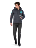 Alpinestars Variegate Hoodie, sudadera de forro polar con cremallera frontal, gris Gunmetal, usada por un modelo con vaqueros negros y zapatillas, con la marca 'ASTARS' en color turquesa y logotipos coloridos en las mangas y el pecho, ropa urbana casual de inspiración motorsport