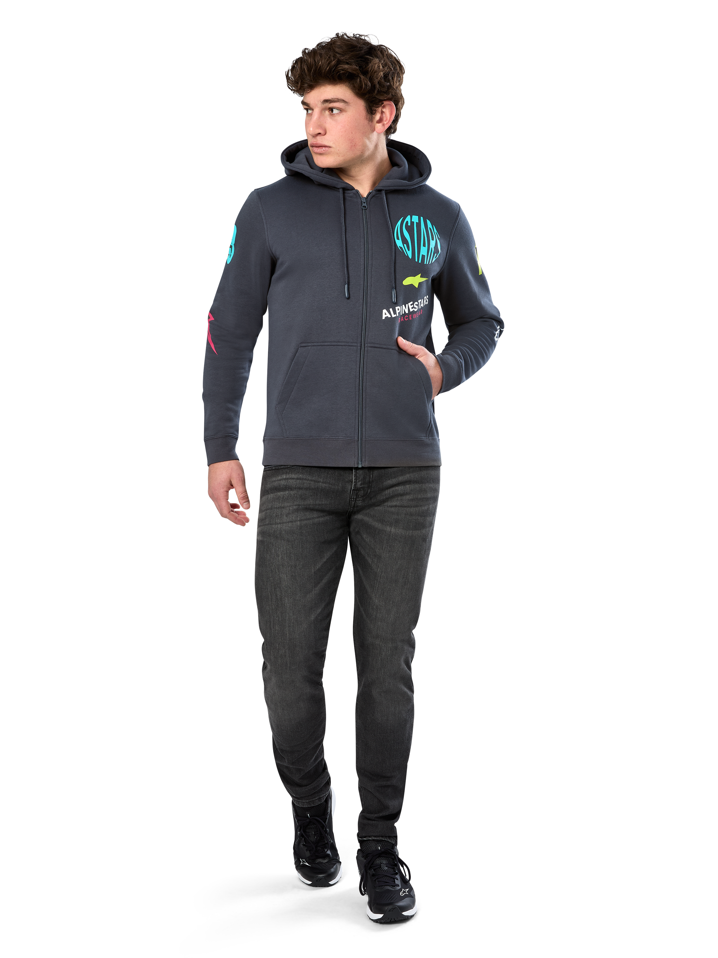 Alpinestars Variegate Hoodie, sudadera de forro polar con cremallera frontal, gris Gunmetal, usada por un modelo con vaqueros negros y zapatillas, con la marca 'ASTARS' en color turquesa y logotipos coloridos en las mangas y el pecho, ropa urbana casual de inspiración motorsport