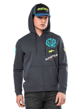 Sudadera Alpinestars Variegate, sudadera de forro polar con cremallera frontal, gris plomo con gráficos de logotipos multicolores en el pecho y las mangas, usada por un modelo con gorra a juego, ropa urbana casual con bolsillos de canguro y cremallera completa