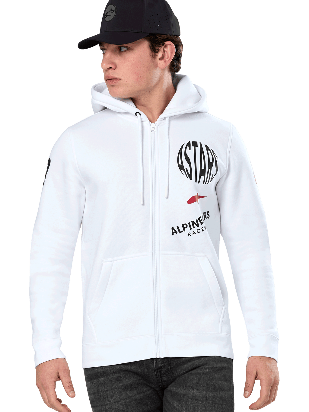 Alpinestars Variegate Hoodie, sudadera blanca con cremallera y capucha, gráficos de carreras ASTARS en negro y rojo, usada por un modelo con gorra negra y vaqueros oscuros, estilo urbano casual de automovilismo con bolsillo canguro y capucha con cordón