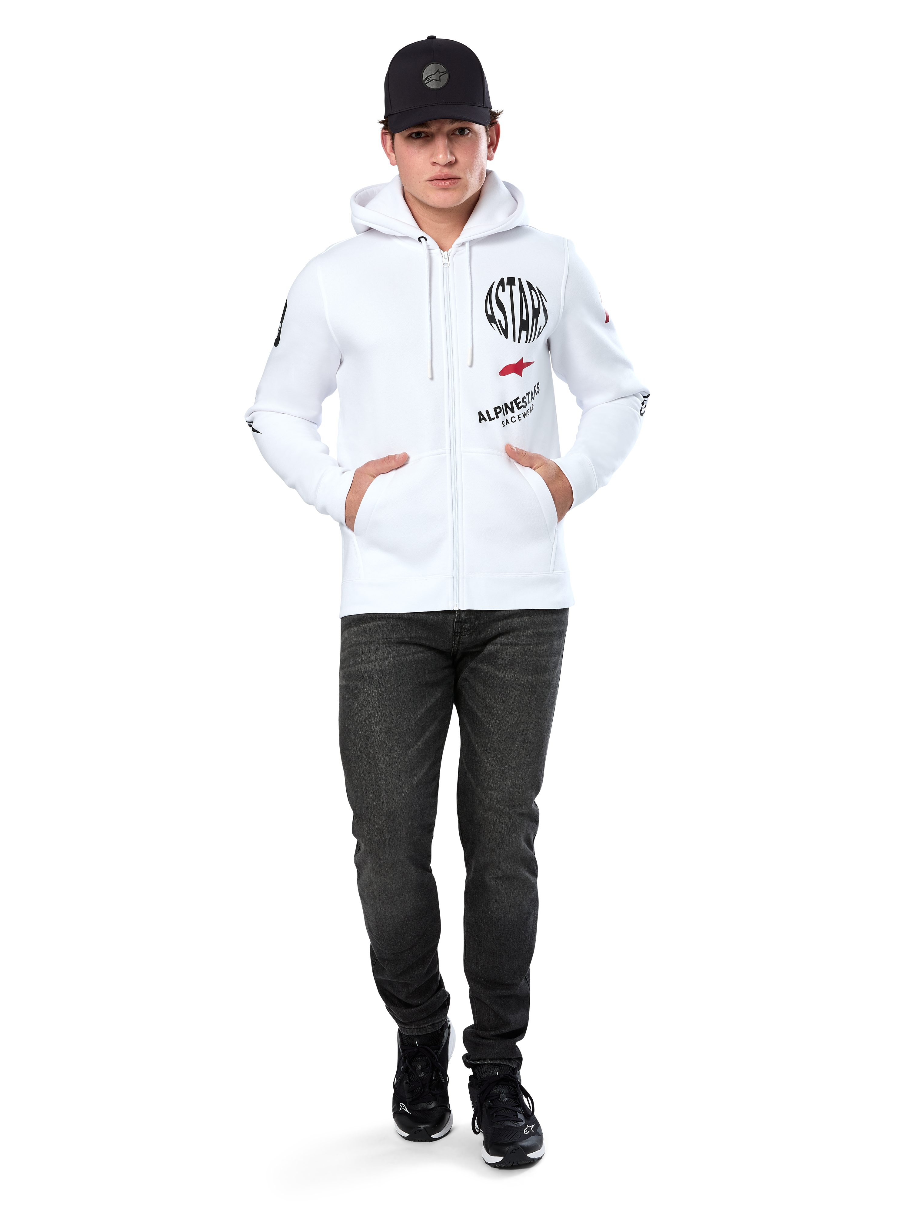 Alpinestars Variegate Hoodie, sudadera blanca de forro polar con cremallera, arte de múltiples logotipos con 'ASTARS' y logotipo de estrella roja en el pecho, detalles gráficos en las mangas, usada por un modelo con gorra negra y vaqueros negros, moda urbana casual de motorsport