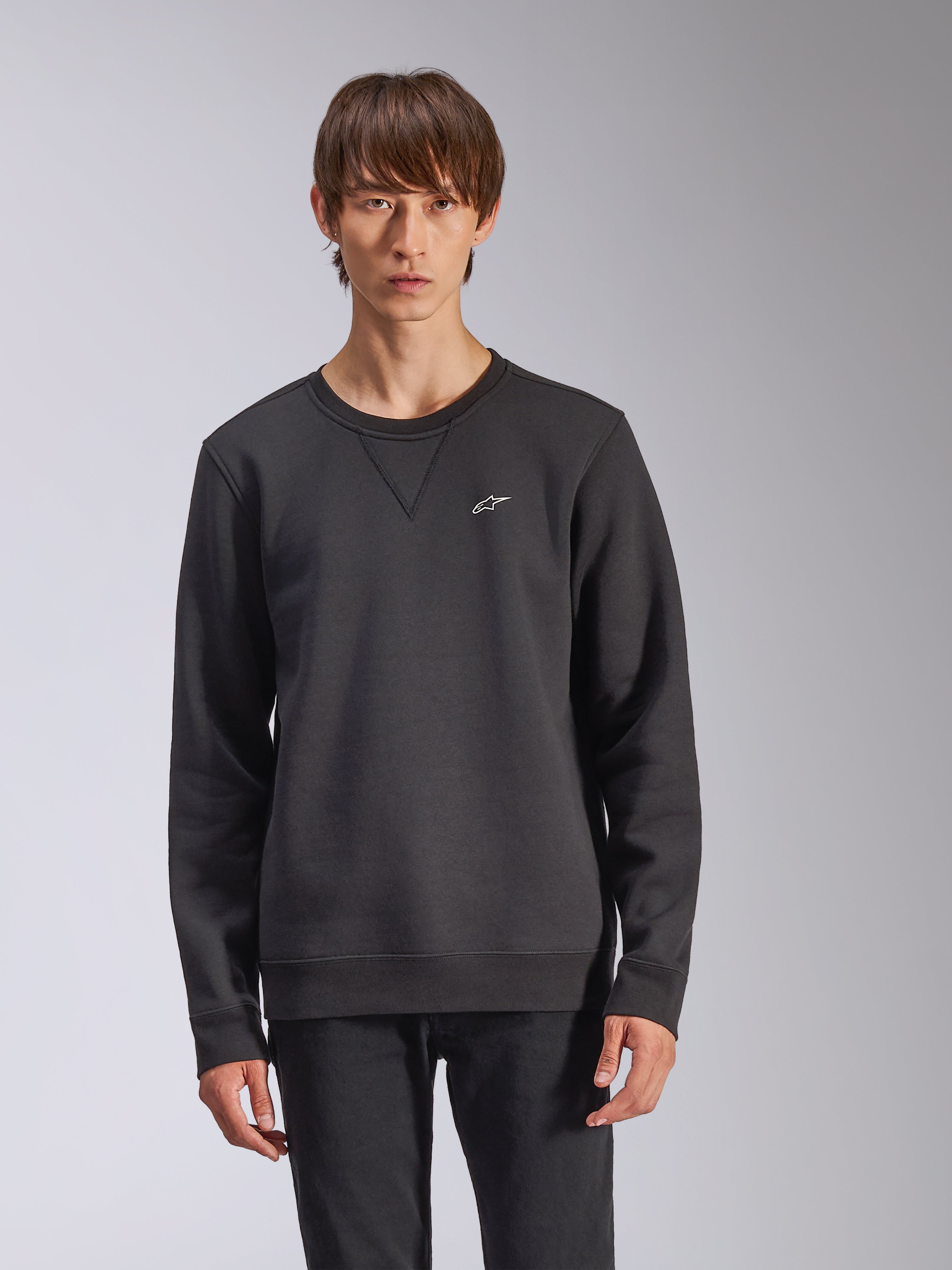 Sudadera Alpinestars Positive Crew, negra, con un pequeño logotipo de estrella Alpinestars blanco en el pecho, detalle de costura en V en el cuello redondo, puños y dobladillo acanalados, estilo urbano casual inspirado en el automovilismo