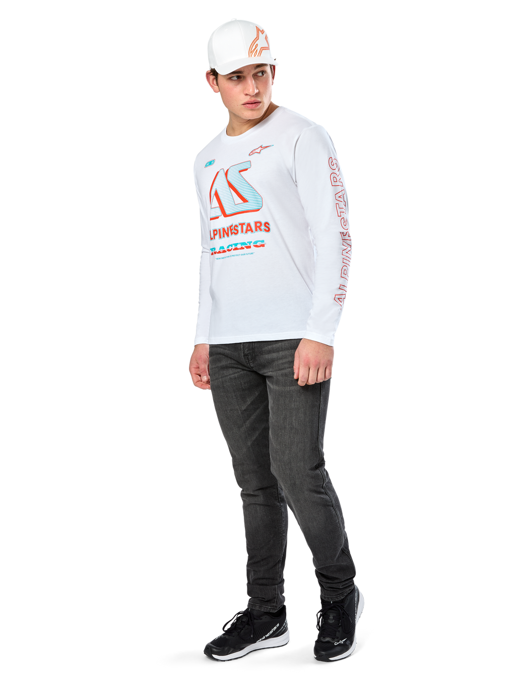 Alpinestars Ayess CSF Tee, camiseta de manga larga blanca, con grandes gráficos de carreras CSF en azul y rojo en el pecho y marca Alpinestars roja en la manga, combinada con vaqueros oscuros y una gorra blanca Alpinestars, estilo streetwear casual de automovilismo
