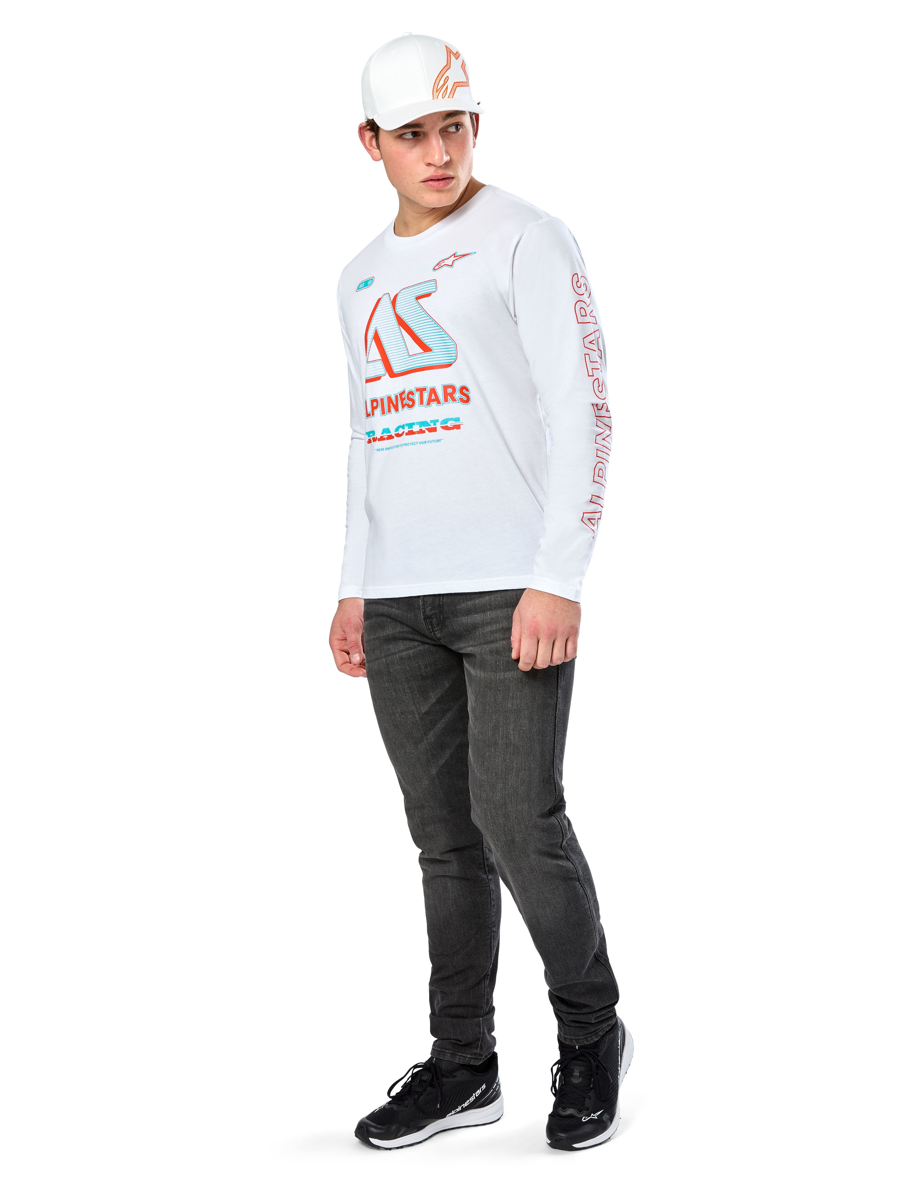 Alpinestars Ayess CSF Tee, camiseta de manga larga blanca, con grandes gráficos de carreras CSF en azul y rojo en el pecho y marca Alpinestars roja en la manga, combinada con vaqueros oscuros y una gorra blanca Alpinestars, estilo streetwear casual de automovilismo