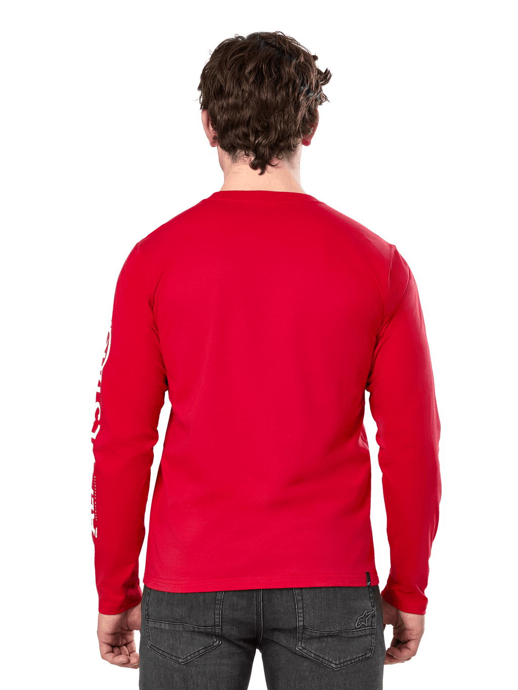 Vista trasera de un hombre con la camiseta de manga larga Alpinestars Committed CSF en color rojo, combinada con vaqueros gris oscuro, con el logotipo de Alpinestars visible en blanco en la manga y un diseño minimalista en la espalda.
