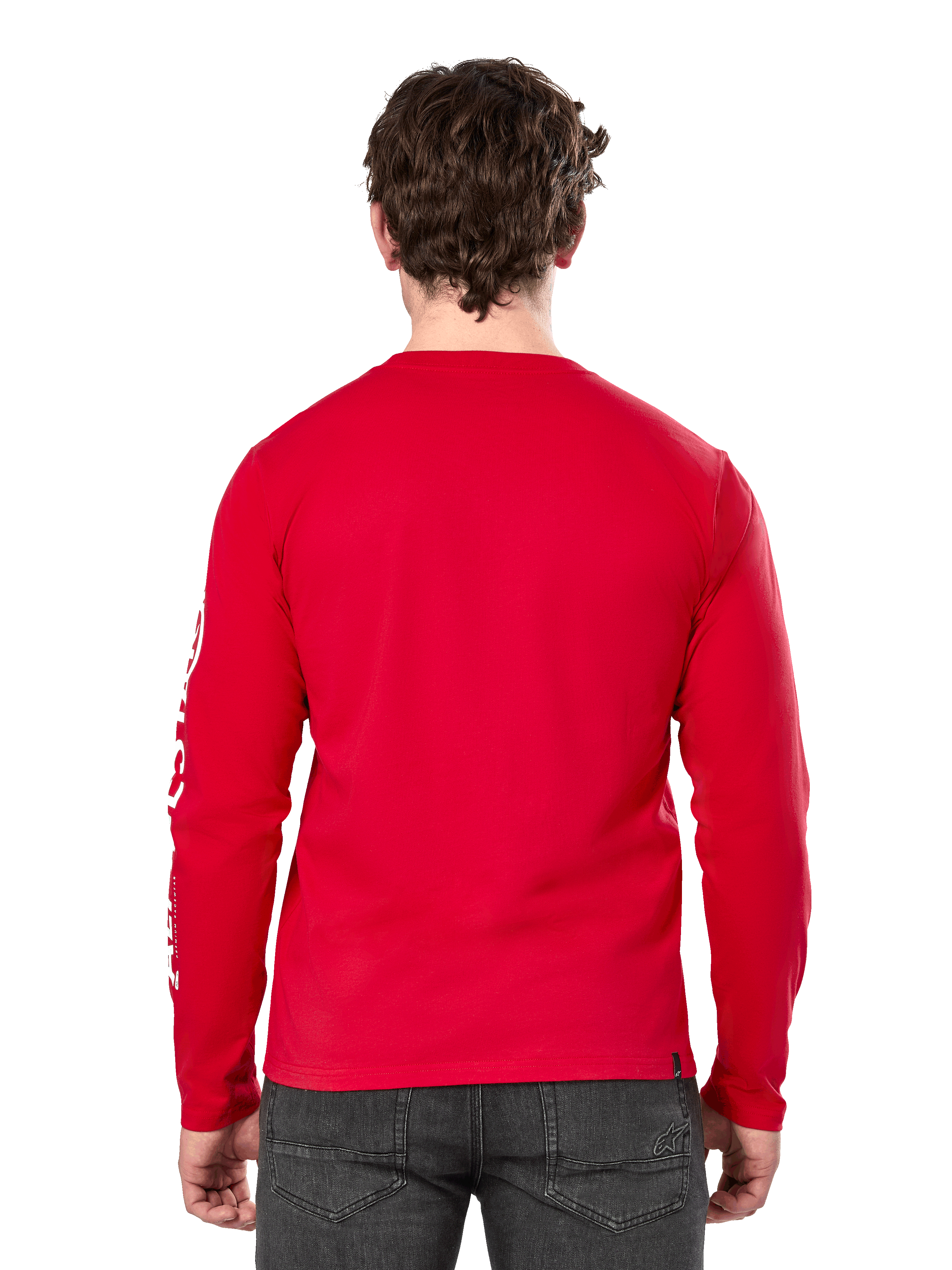 Vista trasera de un hombre con la camiseta de manga larga Alpinestars Committed CSF en color rojo, combinada con vaqueros gris oscuro, con el logotipo de Alpinestars visible en blanco en la manga y un diseño minimalista en la espalda.