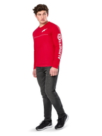 Alpinestars Committed CSF Tee, camiseta de manga larga, roja, con el logotipo Astars blanco en el pecho y la marca Alpinestars en la manga, lucida por un modelo con vaqueros oscuros y zapatillas negras, estilo casual motorsport