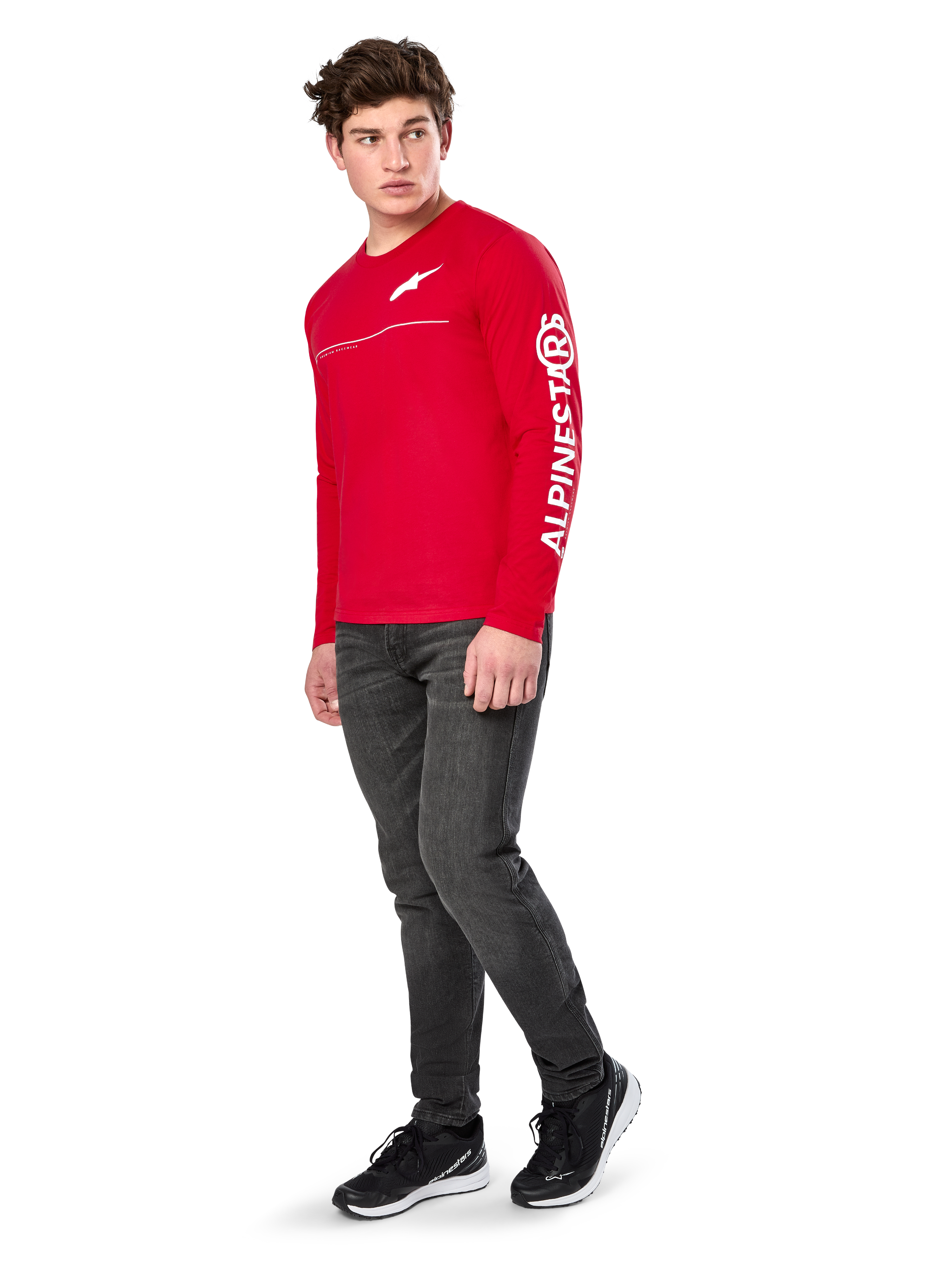 Alpinestars Committed CSF Tee, camiseta de manga larga, roja, con el logotipo Astars blanco en el pecho y la marca Alpinestars en la manga, lucida por un modelo con vaqueros oscuros y zapatillas negras, estilo casual motorsport