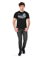 Alpinestars Semicircle CSF Tee, camiseta de manga corta, negra, gráfico curvado en blanco y azul claro en el pecho, usada por un modelo con vaqueros gris oscuro y zapatillas negras, ropa urbana casual de estilo motor