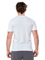Alpinestars Geografica CSF Tee, camiseta de manga corta, blanca, vista posterior, usada por un modelo con pantalones grises, ropa urbana casual estilo motorsport