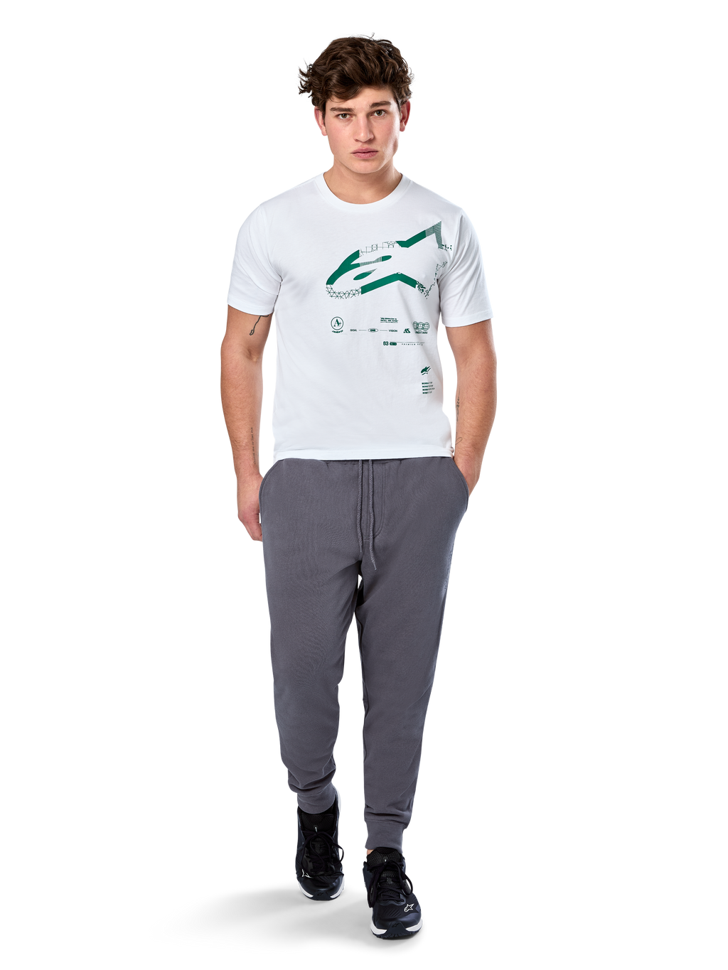 Alpinestars Geografica CSF Tee, camiseta de manga corta, blanca, logotipo Astars verde con gráfico multi-tech geográfico, combinada con pantalones de chándal grises y zapatillas negras, estilo casual de ropa urbana de automovilismo