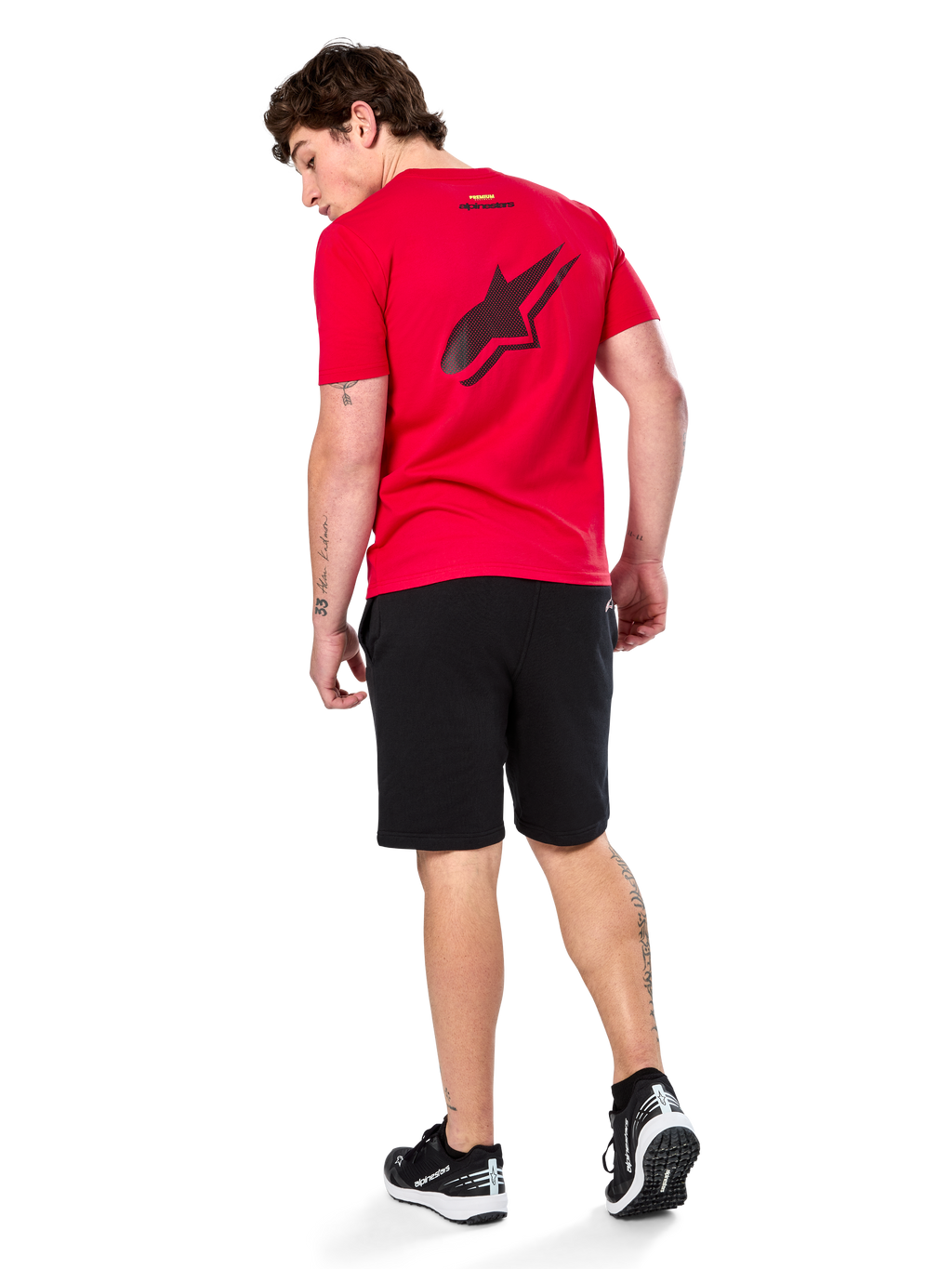 Camiseta Alpinestars Formulate CSF, camiseta de manga corta, roja, logotipo grande de Astars perforado en negro en la espalda, combinada con pantalones cortos negros y zapatillas, ropa urbana informal inspirada en el mundo del motor