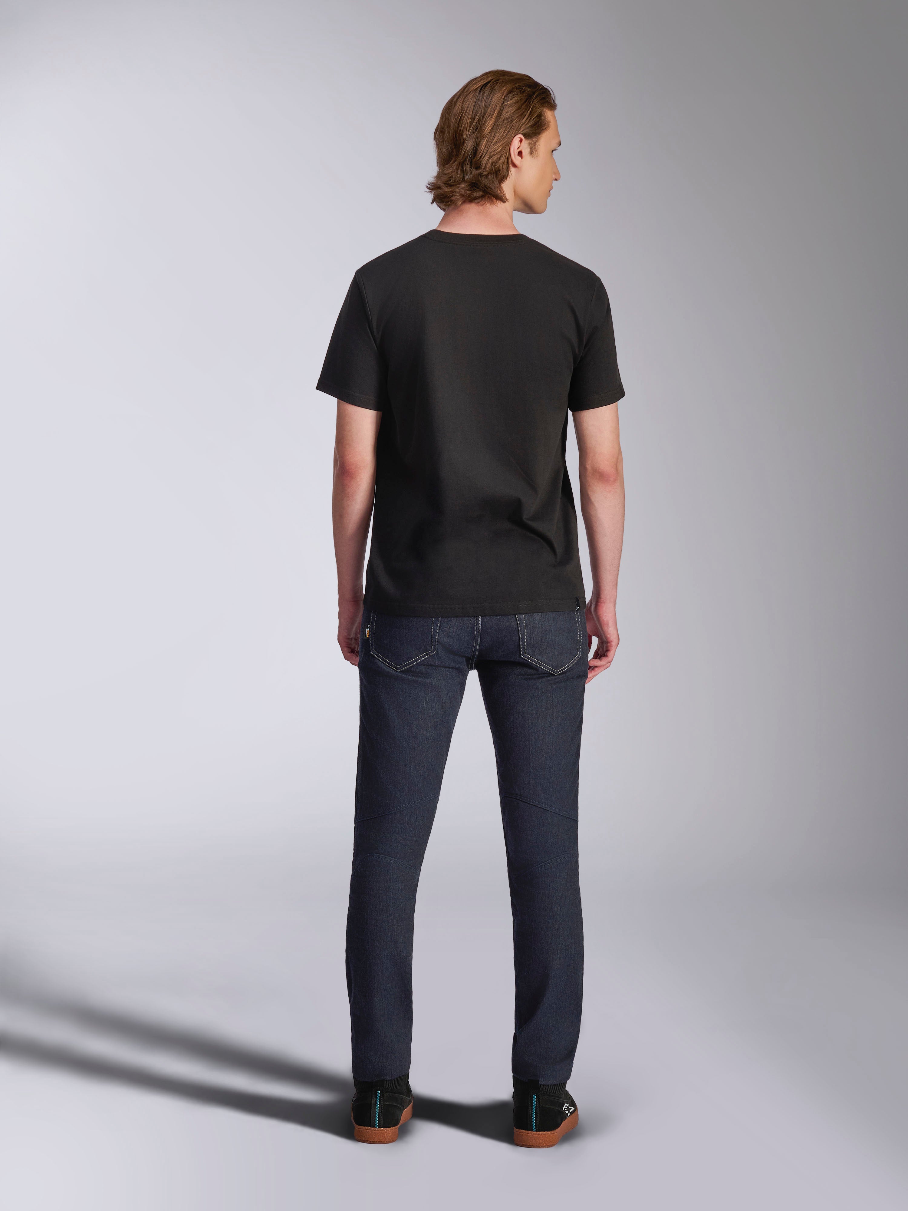 Alpinestars Luxo CSF Tee, camiseta de manga corta, negra, vista posterior, usada por un modelo con pantalones vaqueros oscuros, estilo streetwear casual de motor