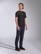 Camiseta Alpinestars Luxo CSF, camiseta de manga corta, negra, logotipo de Astars perfilado en dorado en el pecho, usada por un modelo con vaqueros oscuros y zapatillas negras, ropa de calle casual de automovilismo