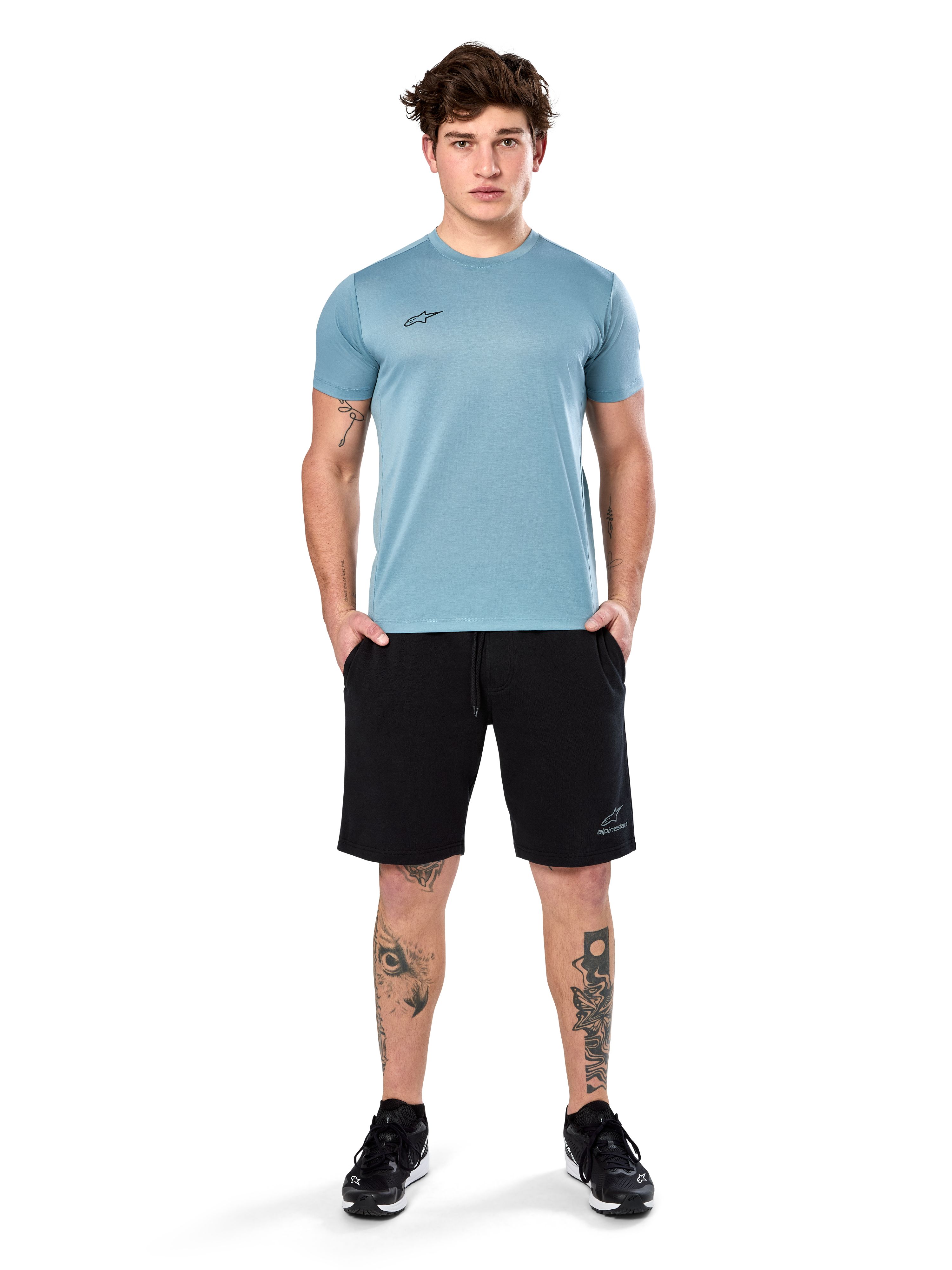 Camiseta Alpinestars Point Performance, camiseta de manga corta, azul hielo, con un pequeño logotipo frontal negro, cuello redondo, usada por un modelo con pantalones cortos y zapatillas negras, ropa deportiva casual con absorción de humedad