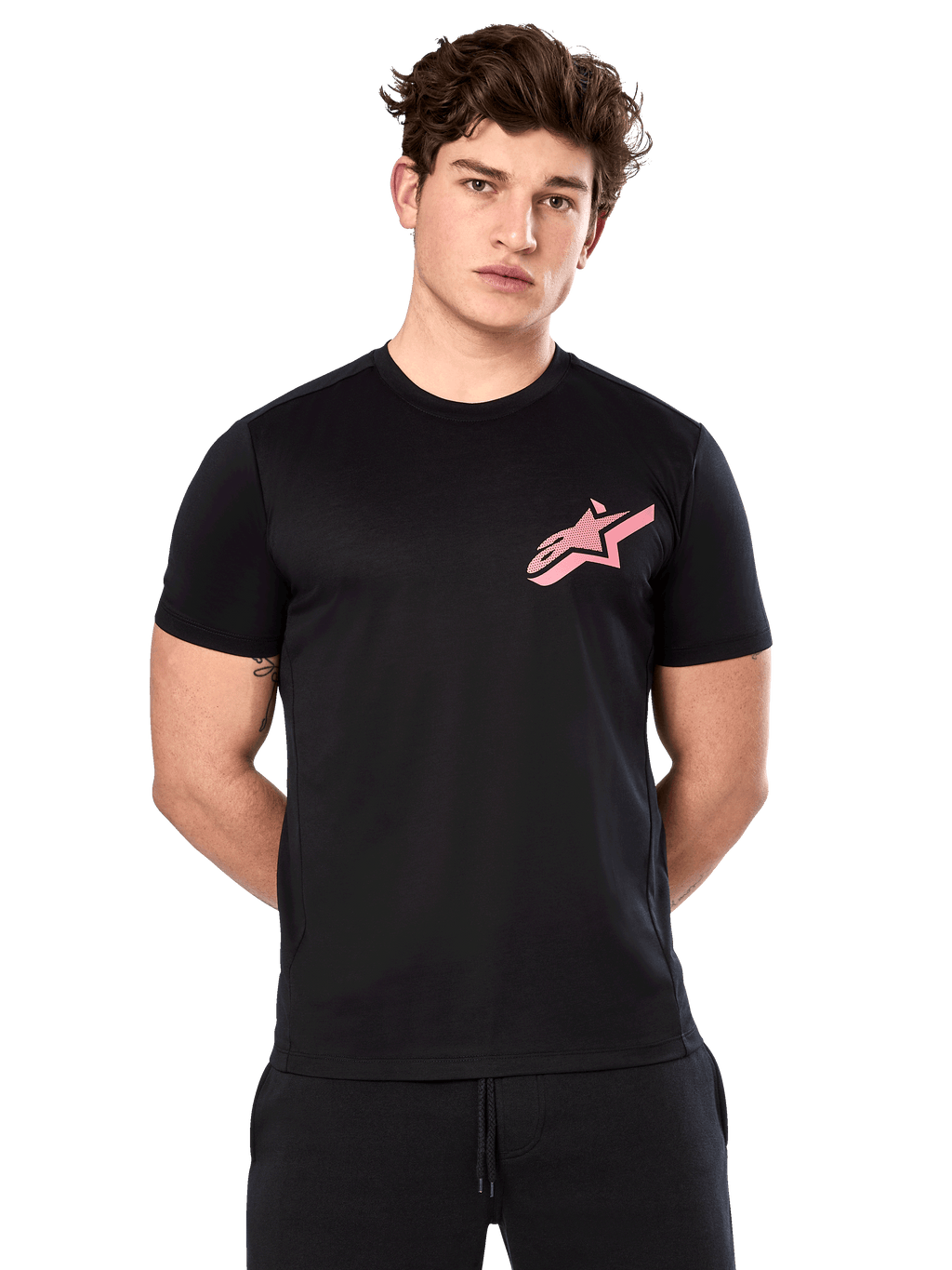 Alpinestars Attrition Performance Tee, camiseta de manga corta para hombre, negra con logo Astars rosa en el pecho, vestida por un modelo masculino, ropa de rendimiento casual para deportes de motor