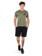Alpinestars Attrition Performance Tee, camiseta de manga corta, verde claro, con un logotipo Astars negro en el pecho, combinada con pantalones cortos deportivos negros y zapatillas negras, imagen de estilo de vida con ropa deportiva casual de alto rendimiento