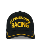 Gorra Alpinestars Luminary, gorra snapback negra, bordado frontal 3D Alpinestars Racing en amarillo, visera curva con ribete de sutache amarillo, accesorio casual de estilo motorsport