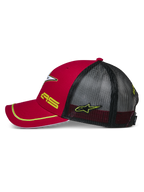 Alpinestars Exceed Trucker Hat, vista lateral en rojo y negro, visera curva con ribete amarillo, paneles traseros de malla negra, bordado de los logos AS y la estrella en amarillo, accesorio casual inspirado en el automovilismo