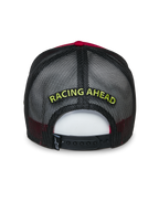 Alpinestars Gorra Trucker Exceed, vista trasera, roja y negra, presenta bordado amarillo "RACING AHEAD" sobre malla negra, cierre snapback ajustable, accesorio deportivo casual