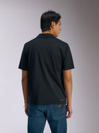 Alpinestars Impetus Sport Polo, Black Short Sleeve Polo Shirt, back view of man wearing polo with blue denim jeans, featuring small Alpinestars wordmark on the lower back, casual motorsport-inspired sportswear