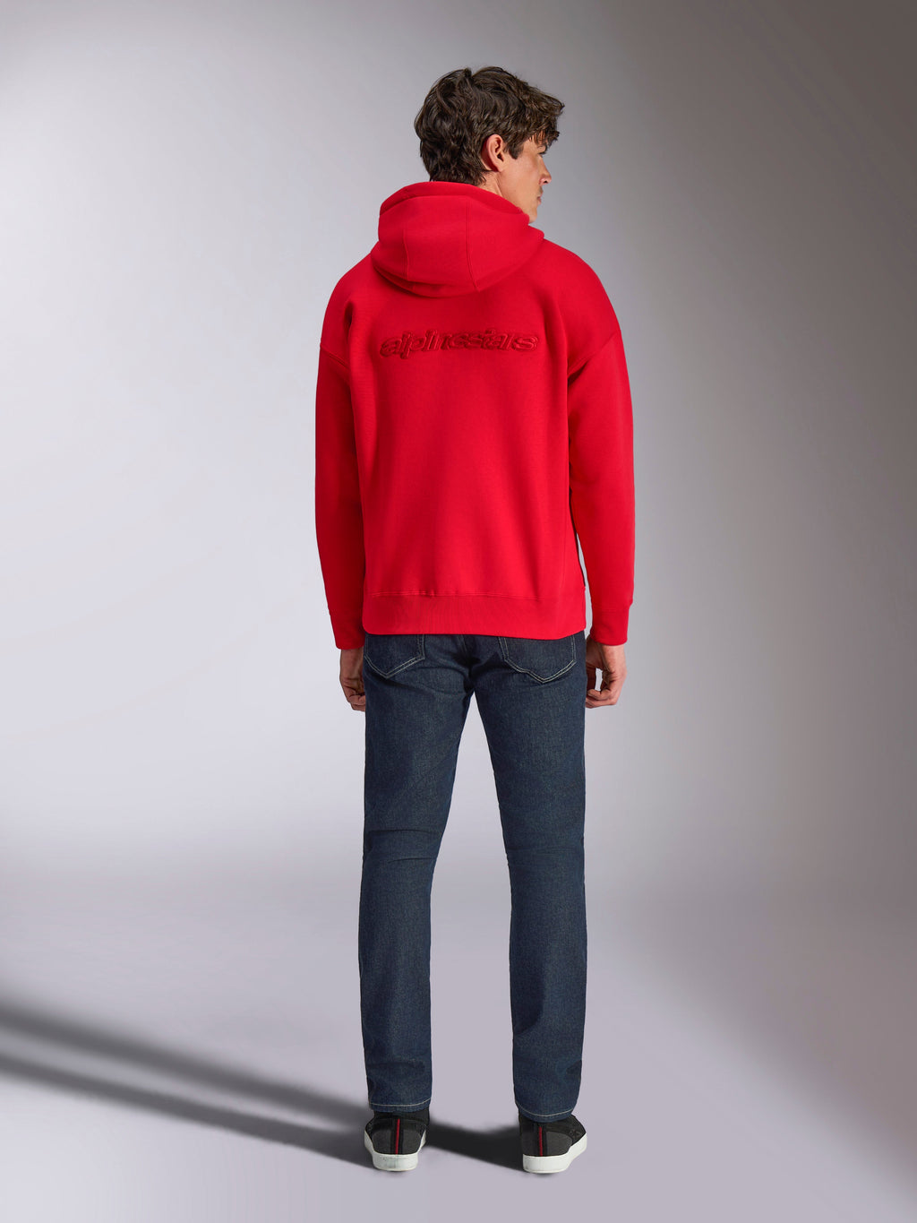 Alpinestars Emergent Oversized Hoodie, Red, back view on male model, featuring tone-on-tone 3D embroidered Alpinestars word logo, worn with dark blue jeans, casual motorsport-inspired streetwear