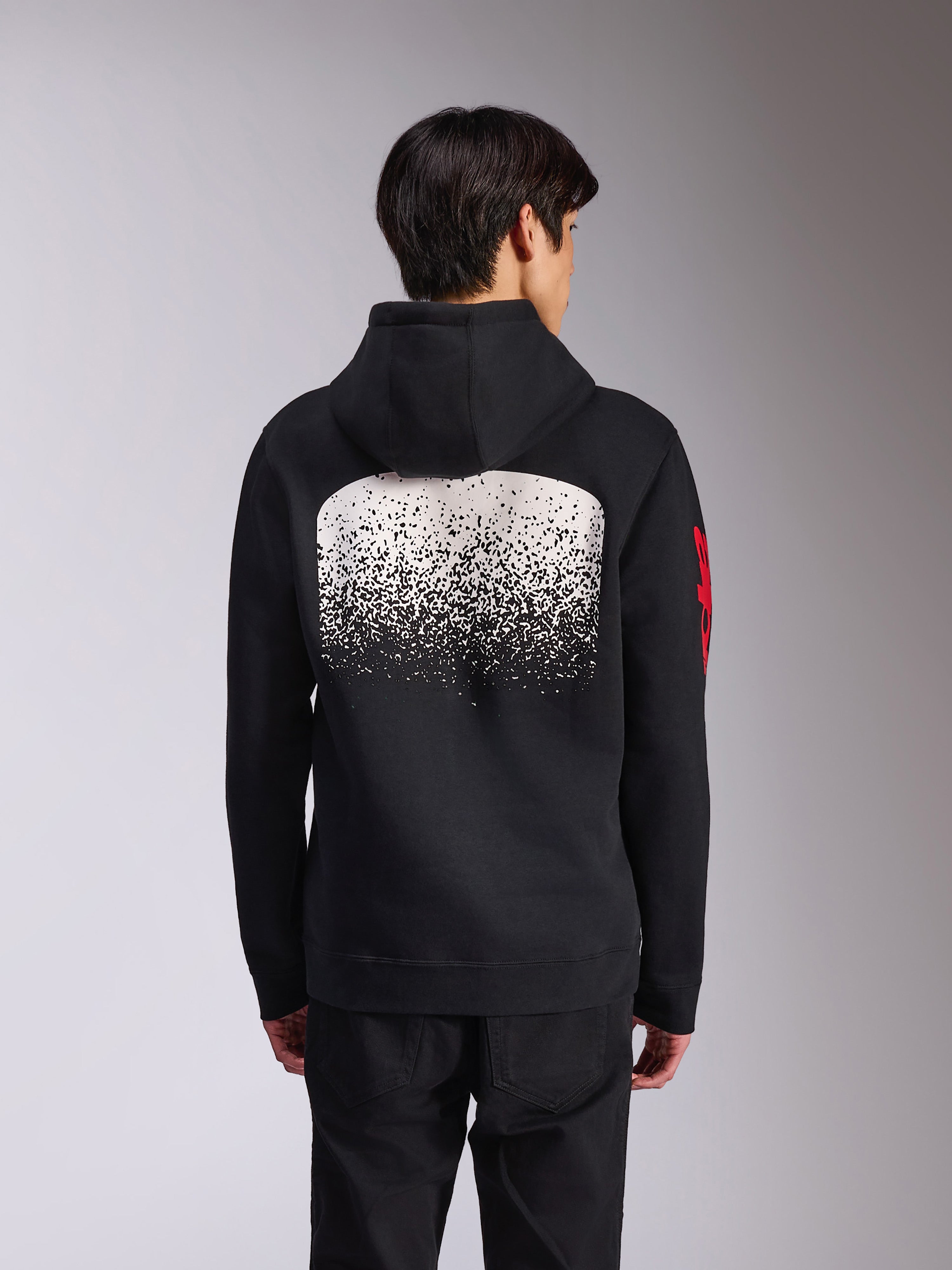 Sudadera con capucha Alpinestars Obsessed, vista trasera de sudadera de forro polar negra, con un gran gráfico de degradado MX moteado en blanco en la espalda y logotipos de Alpinestars en rojo en las mangas, ropa urbana casual inspirada en el automovilismo