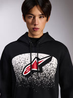 Sudadera con capucha Alpinestars Obsessed, sudadera negra de felpa, con un logotipo Astars rojo y blanco dentro de un gráfico degradado MX punteado en blanco en el pecho, usada por un modelo, estilo casual motorsport con capucha ajustable con cordón