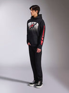 Alpinestars Obsessed Hoodie, sudadera de forro polar negro con un gran gráfico moteado en blanco en el pecho, logotipo Astars en rojo y marca roja en la manga, usada por un modelo con pantalones negros y zapatillas, estilo casual motorsport