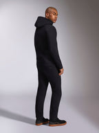 Alpinestars Ellipsoid Hoodie, ropa urbana casual negra, vista trasera en modelo masculino, sudadera de forro polar con capucha, puños y dobladillo de canalé, combinada con pantalones negros y zapatillas, diseño moderno inspirado en el automovilismo